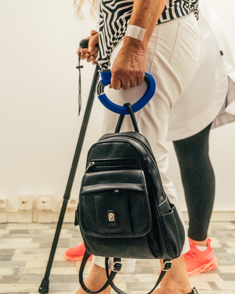 Patientin mit Gehstock und Rucksack, daneben Ergotherapeutin Mareike Grimm