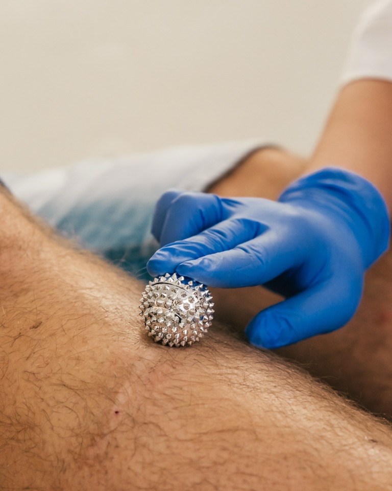 Igelball wird über das Bein eines Patienten gerollt