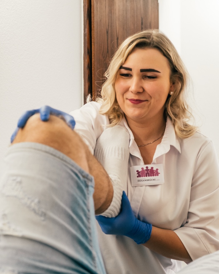 Mareike Grimm mobilisiert lächelnd das Knie eines Patienten