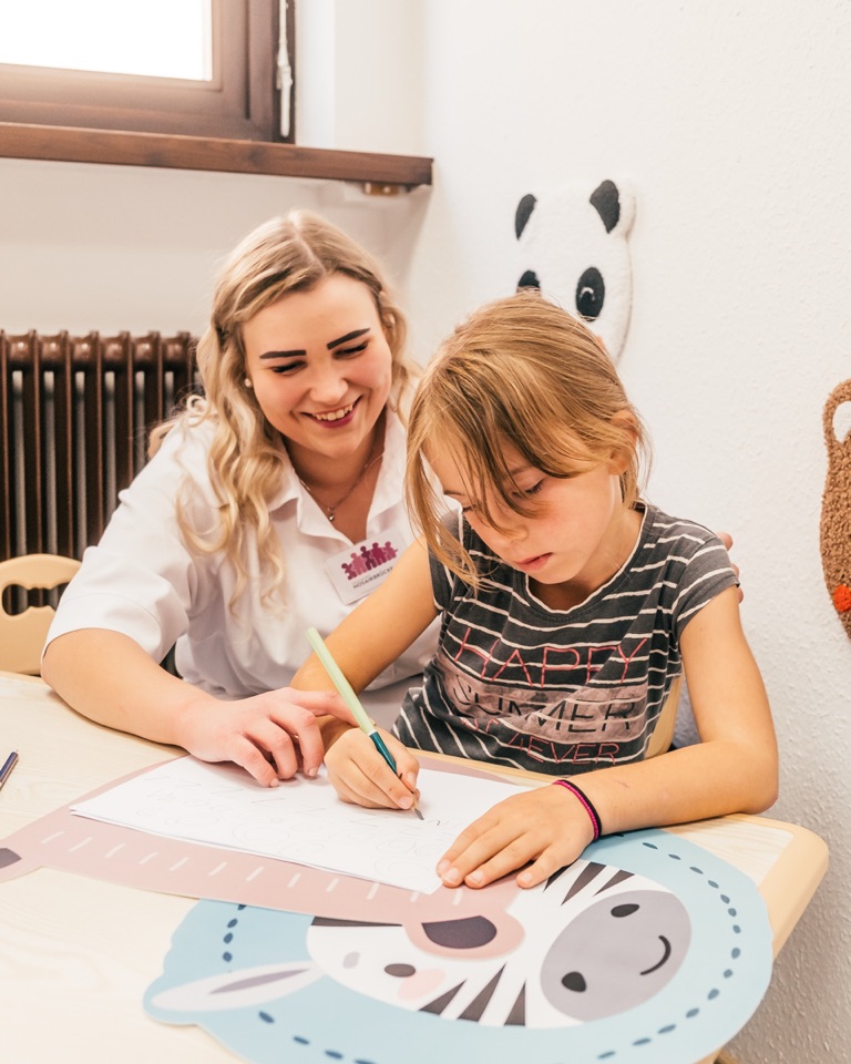 Mareike Grimm malt mit einem Mädchen am Tisch